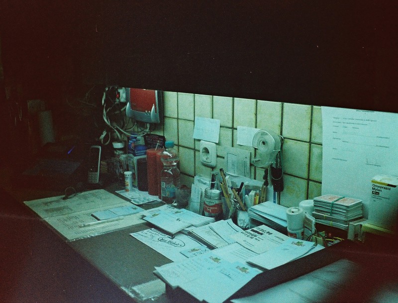 Ein analoges Farbfoto von der Theke im Zenetti Pils. Zu sehen sind ganz viele Unterlagen, Steckdosen, Bierdeckel, ein Router und eine Speisekarte.